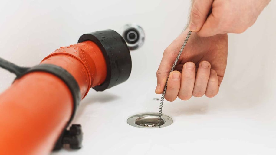 Encanador usando cobra de drenagem