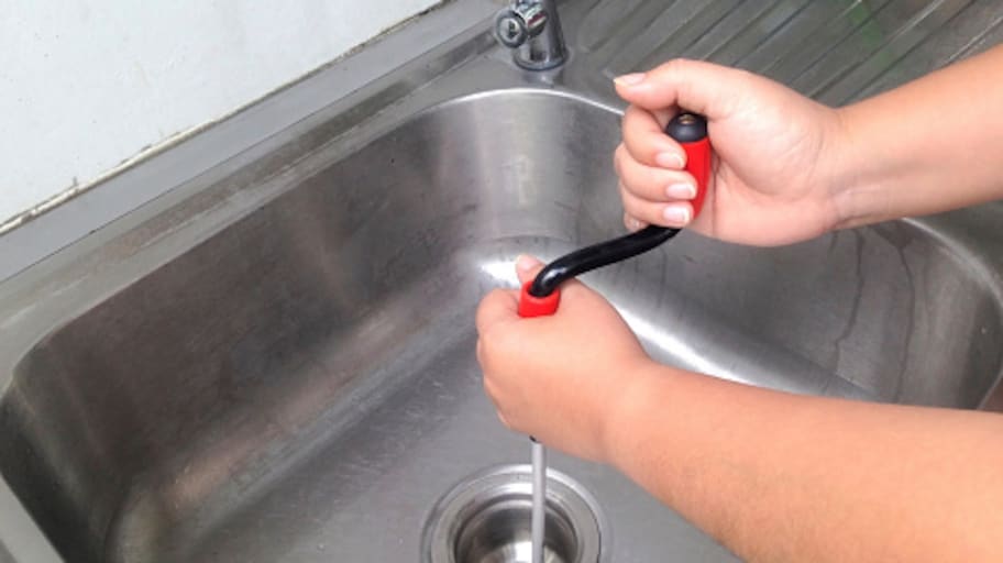 Mulher usa cobra para desentupir pia de cozinha